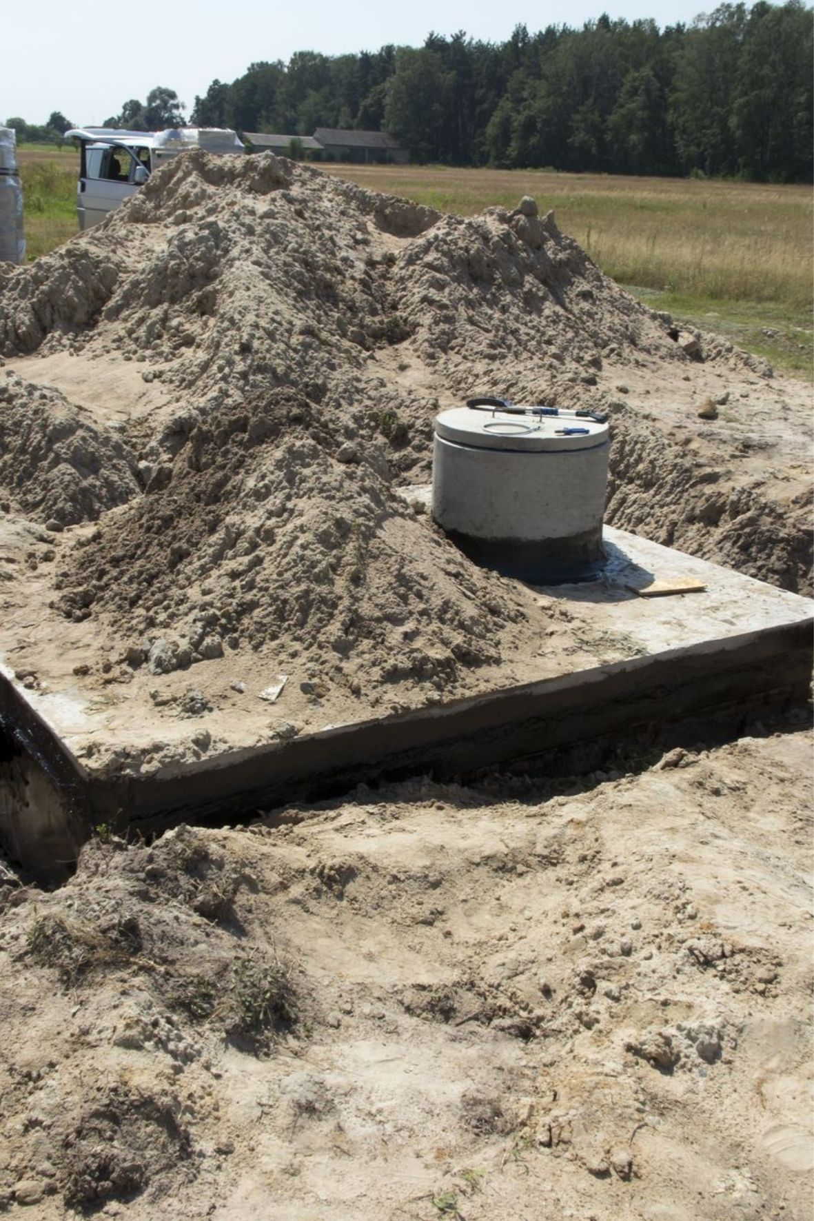 Regard en béton installé sur un terrain excavé dans un environnement résidentiel et rural à Saint-Pie