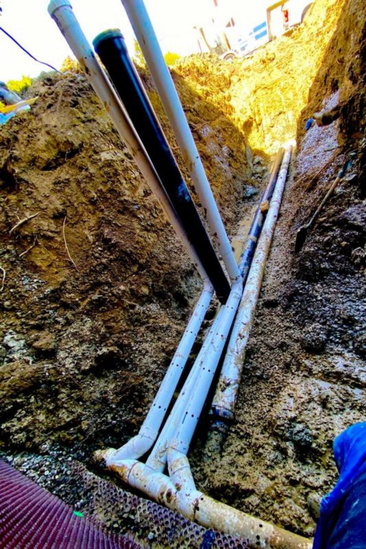 Conduites souterraines apparentes dans une tranchée avec sol excavé et matériaux visibles au Québec